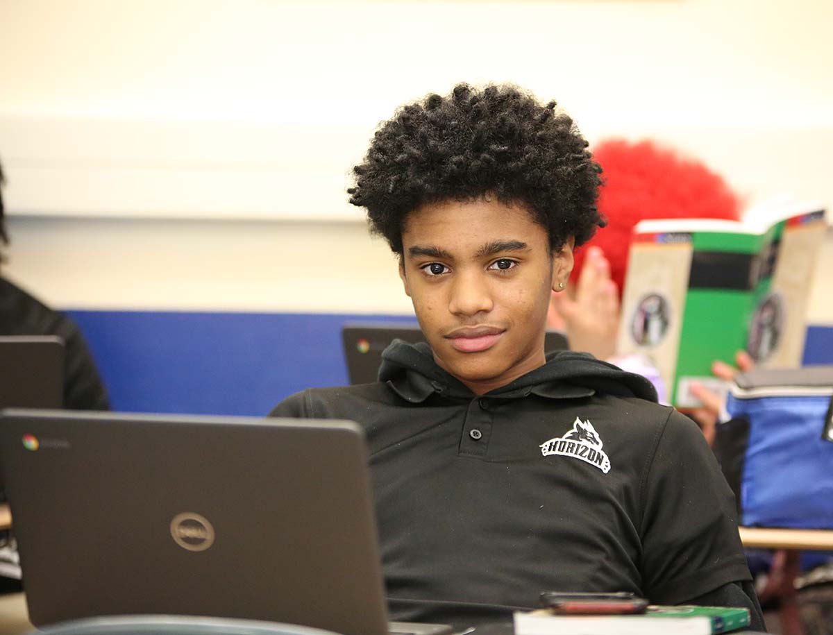 Elementary student smiling and posing together in a classroom.